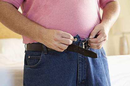 Overweight man buttoning his jeans. Overweight man buttoning his jeans.