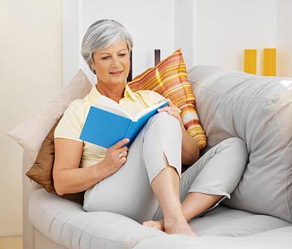 Mature woman on a sofa reading a book Mature woman on a sofa reading a book