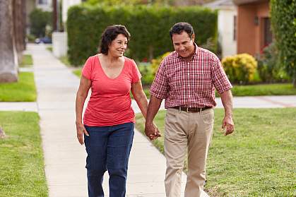 Senior Hispanic couple walking and holding hands on a sidewalk Senior Hispanic couple walking and holding hands on a sidewalk