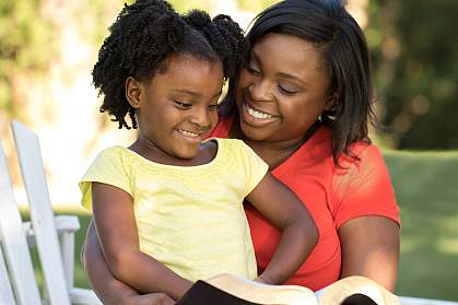 African-American mother and daughter reading outdoors. African-American mother and daughter reading outdoors.