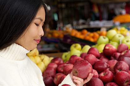 Young woman at store looking at apples Young woman at store looking at apples