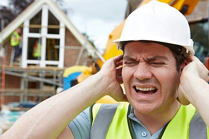 Construction worker holding ears on building site Construction worker holding ears on building site