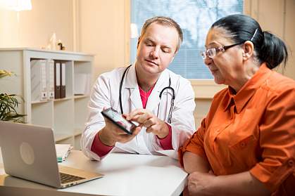 Doctor showing woman something on a tablet.