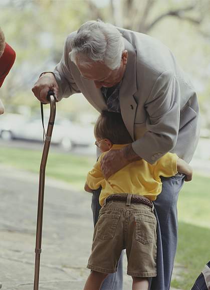 Grandfather with a cane hugged by a child Grandfather with a cane hugged by a child
