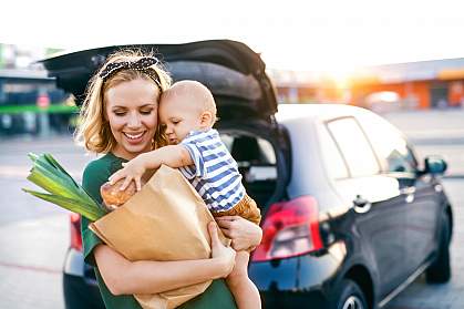 Young mother with baby boy carrying groceries to car Young mother with baby boy carrying groceries to car
