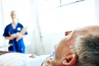 Elderly man in hospital bed Elderly man in hospital bed with a blurred image of a nurse in the background