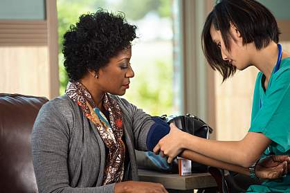 Health care worker setting up to take a woman’s blood pressure Health care worker setting up to take a woman’s blood pressure.