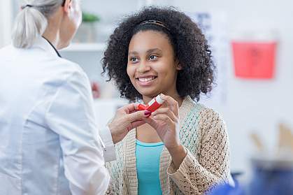 Teenage girl learning to use inhaler