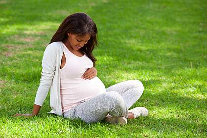 Pregnant woman sitting on green grass Pregnant woman sitting on green grass