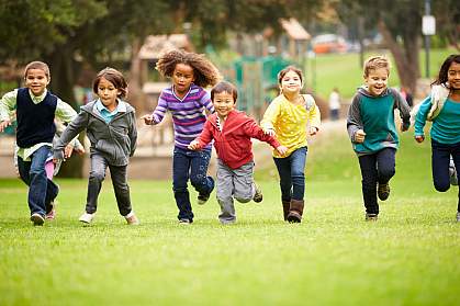 Group of children running over playground grass Group of children running over playground grass