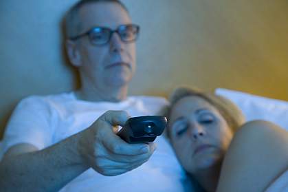 Sleepy couple watching TV in bed Sleepy couple watching TV in bed