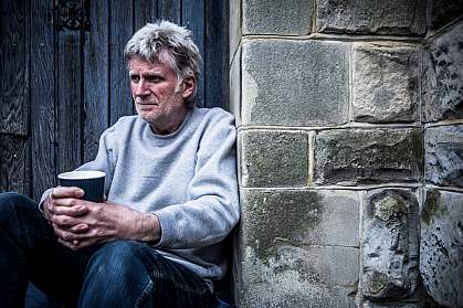 Concerned-looking man leaning on a wall and drinking a beverage Concerned-looking man leaning on a wall and drinking a beverage