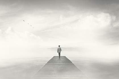 Dream-like photo of man reaching the end of a boardwalk in heavy fog Dream-like photo of man reaching the end of a boardwalk in heavy fog