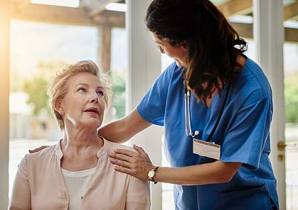 Nurse smiling as she talks to a woman 