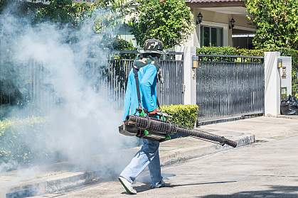 Worker spraying insecticide on a residential street Worker spraying insecticide on a residential street