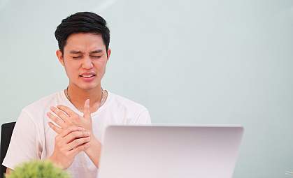 Young man in pain massaging his hand Young man in pain massaging his hand
