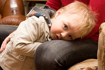 Young boy hiding between a parent’s knees Young boy hiding between a parent’s knees