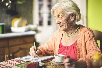 Senior woman in the kitchen writing in a notebook Senior woman in the kitchen writing in a notebook