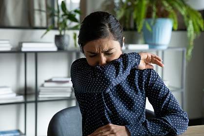 Young woman coughing into her elbow Young woman coughing into her elbow