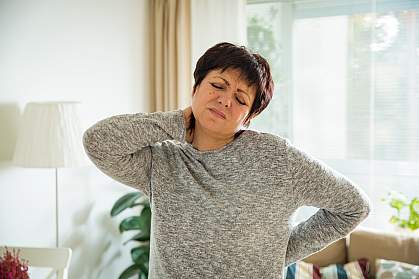 Mature woman holding her back and neck in pain Mature woman holding her back and neck in pain