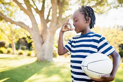 Young child using an inhaler and holding a ball Young child using an inhaler and holding a ball