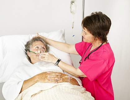 Hospital nurse helping senior woman breath through an oxygen mask