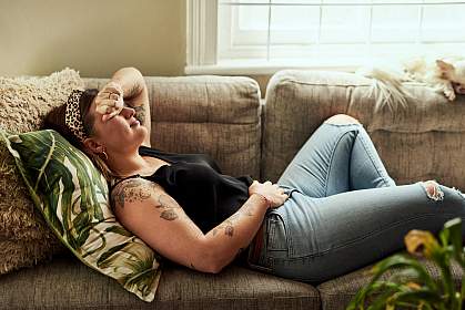 Woman lying on sofa holding her stomach Woman lying on sofa holding her stomach