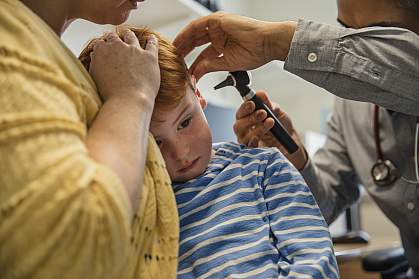 Boy’s ear being examined by a doctor with an otoscope Boy’s ear being examined by a doctor with an otoscope