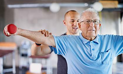 Physiotherapist helping a senior man with weights