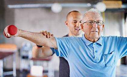 Physiotherapist helping a senior man with weights Physiotherapist helping a senior man with weights