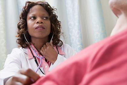 Doctor listening to patient in hospital bed with stethoscope Doctor listening to patient in hospital bed with stethoscope