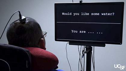 Man with neuroprosthesis Rear view of man with an electrode array in his head watching a screen with words.
