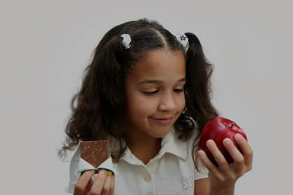 A girl deciding what to eat, with chocolate in one hand and an apple in the other. A girl deciding what to eat, with chocolate in one hand and an apple in the other.