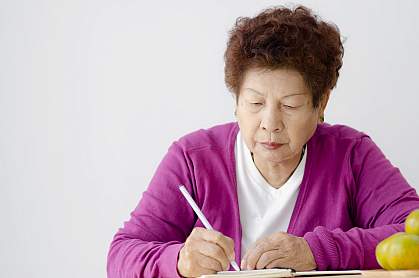 Asian senior woman writing in book Asian senior woman writing in book