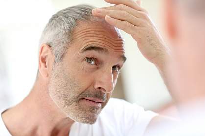Older man looking at his hair in a mirror Older man looking at his hair in a mirror