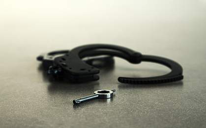 Handcuffs open on table with key in foreground Handcuffs open on table with key in foreground