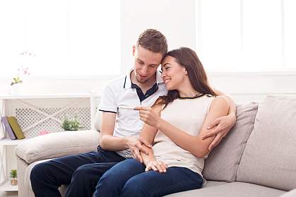 Young couple looking at pregnancy test on couch Young couple looking at pregnancy test on couch