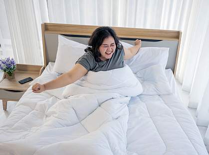 Woman stretching in bed after waking up Woman stretching in bed after waking up