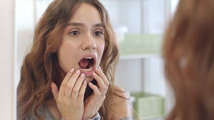 Woman checking the inside of her mouth in a mirror Woman checking the inside of her mouth in a mirror