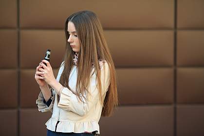 Teen looking skeptically at an electronic cigarette Teen looking skeptically at an electronic cigarette