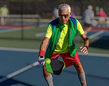 Senior man hitting a pickleball with paddle Senior man hitting a pickleball with paddle