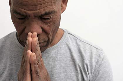 Black man with hands together in thought or prayer Black man with hands together in thought or prayer