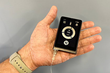 Hand holding a device that looks like a small smartphone Hand holding a device that looks like a small smartphone