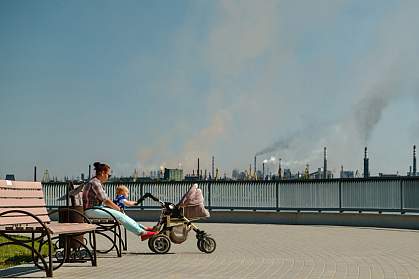 Woman with baby sitting on a bench in a polluted city Woman with baby sitting on a bench in a polluted city