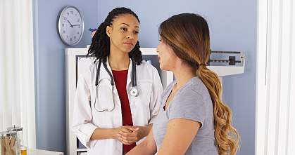 Doctor talking to young female patient in exam room.