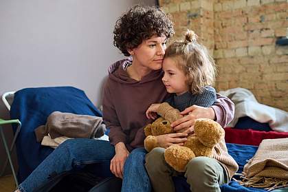 Young woman comforting boy on a cot.