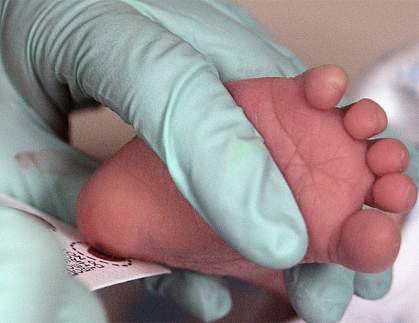 Health care worker collecting a blood sample from a newborn’s heel.