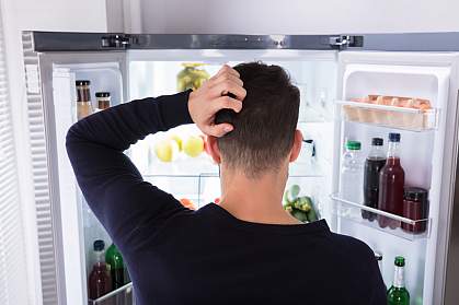 Rear view of a confused man looking at food in refrigerator. Rear view of a confused man looking at food in refrigerator.