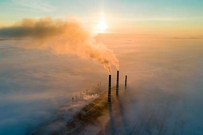 Aerial view of coal power plant with dark smoke at sunset.