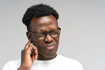 Young Black man touching his ear in distress. Young Black man touching his ear in distress.